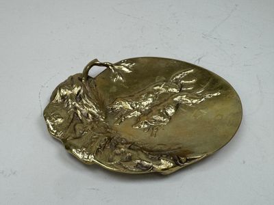 plaque en laiton représentant un oiseau, posée sur un fond blanc
