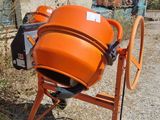an orange cement mixer sitting in front of a building