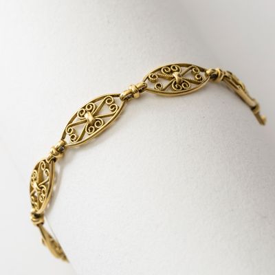 gros plan d'un bracelet en or sur une surface blanche