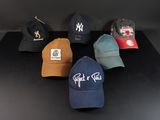 six casquettes de baseball sont alignées sur une surface noire