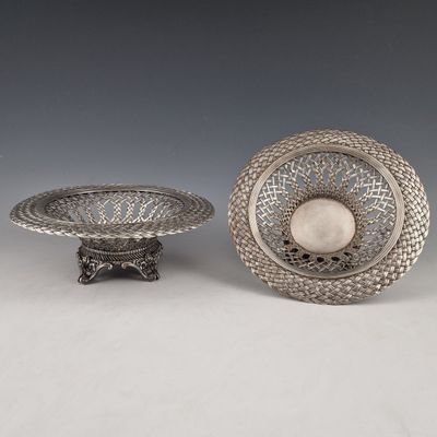 two silver dishes and a bowl on a stand on a white surface