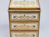 une image représentant une petite commode ornée de motifs dorés et blancs