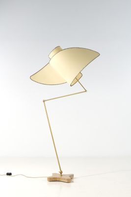 un lampadaire doré avec un pied en bois et un fond blanc