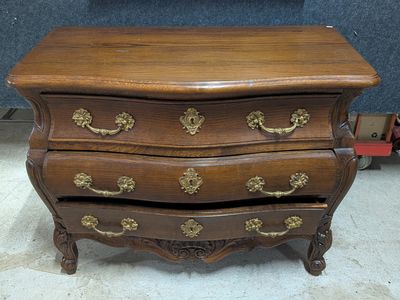 une commode en bois surmontée de ferrures en laiton