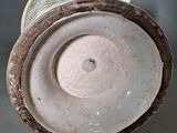 a close up of a vase on a table with a gray background
