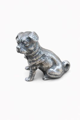 figurine en argent représentant un chien assis sur une surface blanche