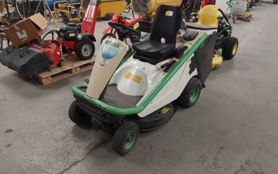 a lawn mower parked in a garage with other lawn mowers in the background