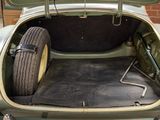 a green car with its trunk open and a tire in the trunk