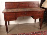 a wooden desk with drawers and a lamp next to it