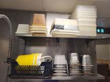 a metal shelf with dishes and cups on it in a kitchen