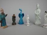 five figurines of asian people and a peacock