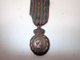 an old medal with a red and green ribbon on a white surface