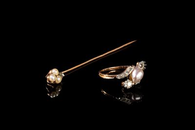 deux bagues en or ornées de perles et de diamants sur fond noir