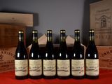six bottles of wine are lined up on a red table cloth