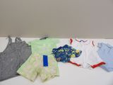 une pile de vêtements de bébé posée sur une table à côté d'un téléphone portable