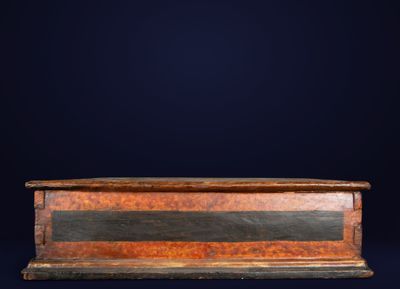 an old wooden casket with a black and brown stripe on it