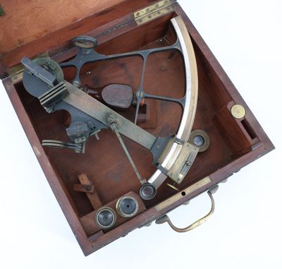 un vieux sexet en laiton dans un coffret en bois posé sur une surface blanche