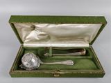 une cuillère en argent et un repose-cuillère dans une boîte verte