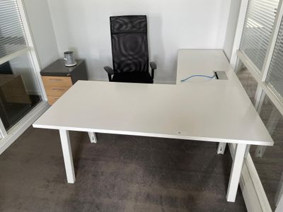 a white desk with a black chair in the corner