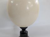 une image représentant une boule blanche posée sur un socle noir, le tout sur fond blanc