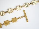 two pieces of jewelry that are on a white surface