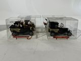 pair of antique model cars in clear boxes on white surface