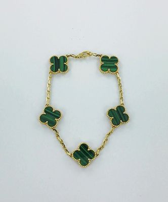 un bracelet vert orné de quatre breloques en forme de trèfle, montées sur une chaîne dorée