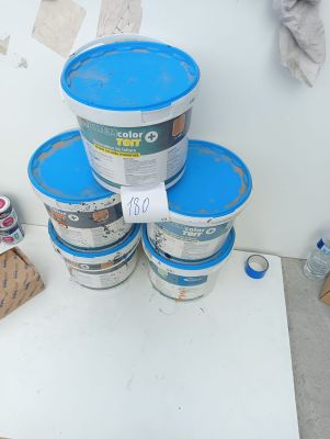several buckets of paint sitting on top of a table next to a wall