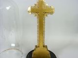a gold cross on a black base next to a glass dome