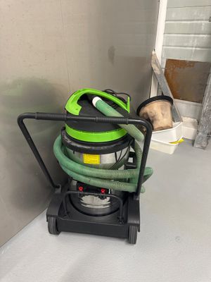 un aspirateur vert et noir posé par terre à côté d'un chien