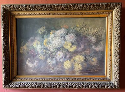 un tableau représentant des fleurs, dans un cadre doré, accroché à un mur rose
