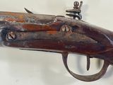 an old gun with a wooden handle on a white wall