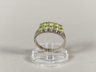 a close up of a ring with three green stones on it