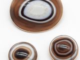 trois morceaux de verre marron et blanc posés sur une surface blanche