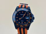 une montre orange et noire posée sur un socle, sur une surface blanche