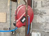 une borne d'incendie rouge et un tuyau bleu fixé au mur
