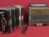 two old accordions sitting on a red cloth with a red background