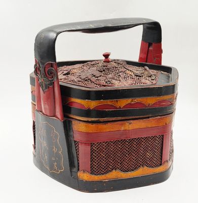 une boîte noire et rouge munie d'une poignée, sur fond blanc