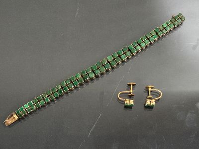 bracelet and earring set with green stones on a black surface