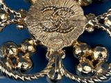an image of a gold broochle with flowers and leaves on a blue background