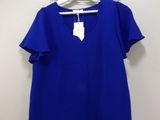 a blue t - shirt hanging on a hanger in front of a white wall