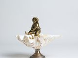 an antique bronze figurine of a woman sitting on a shell