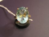 a ring with a blue topaz stone on a black surface