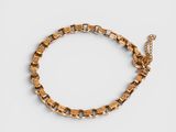 un bracelet en chaîne dorée à maillons carrés sur fond blanc