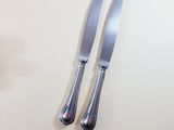 two knives and a fork on a white table
