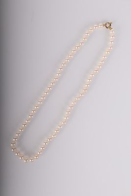 un collier de perles blanches avec un fermoir en or sur fond blanc