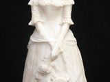 a white statue of a woman with a purse on a black background