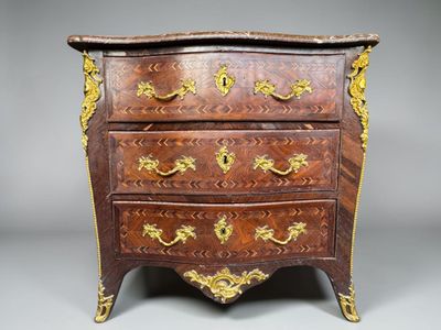 a small chest of drawers with gold decorations on it