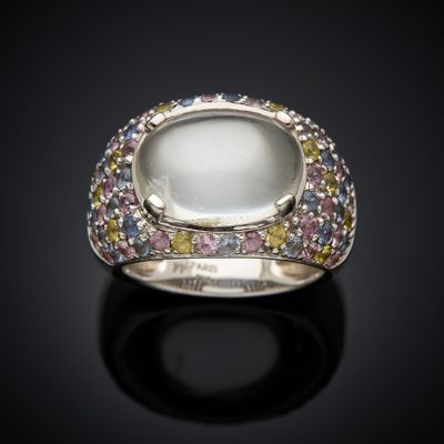 a close up of a ring with a white stone surrounded by multi colored stones
