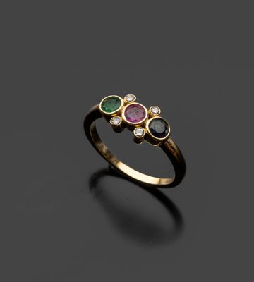 gros plan d'une bague en or avec trois pierres de couleurs différentes